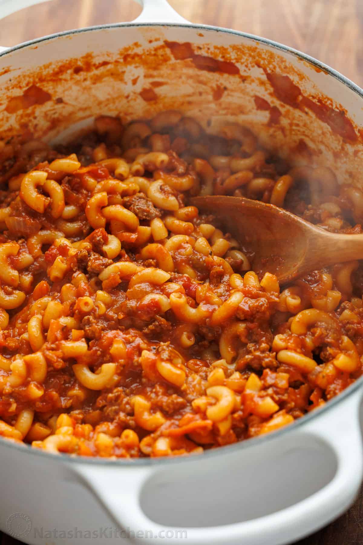 An easy, one-pot American Goulash with saucy ground beef, macaroni pasta, and cheese. It tastes like a homemade hamburger helper! Dutch oven filled with American Goulash with ground beef, tomatoes and elbow macaroni pasta