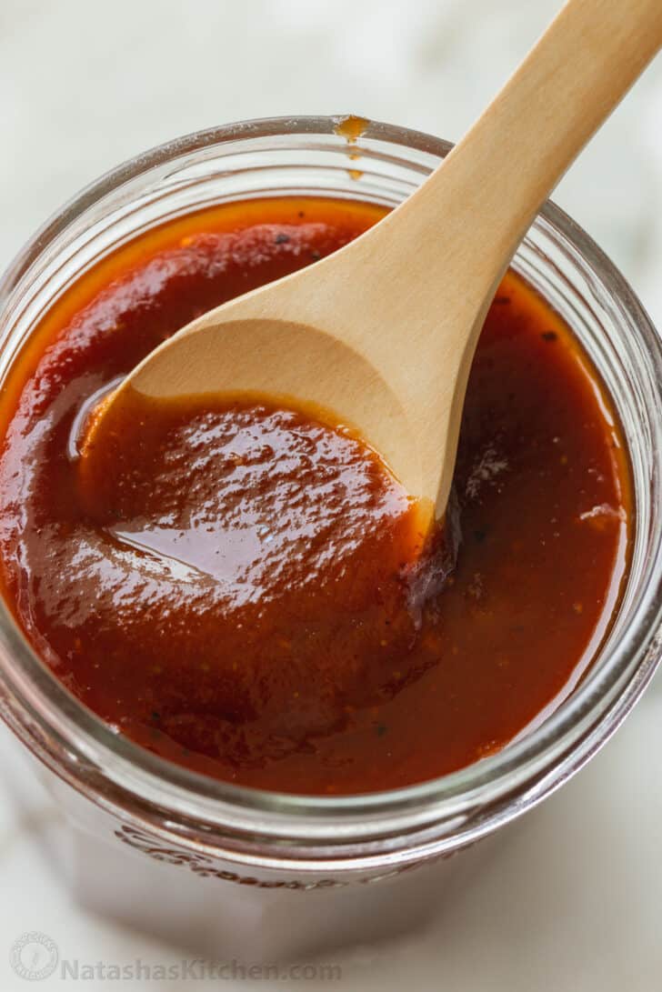 Not only is this homemade BBQ sauce the best you'll ever have, it's also much cheaper than buying it at the store. So easy to make, too! Jar of homemade BBQ sauce with wooden spoon