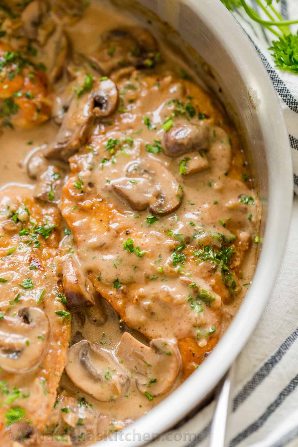 This classic Italian Chicken Marsala is an easy 30-minute chicken dinner. Juicy pan-seared chicken in a creamy mushroom marsala wine sauce. Close-up of Chicken Marsala topped with mushrooms and parsley in a pan