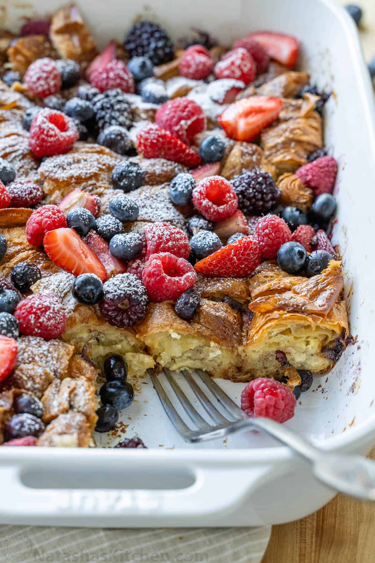 Easy Croissant French Toast Casserole with fresh berries is the best crowd-pleasing breakfast recipe. Refrigerate overnight for easy serving. slice out of a berry-topped breakfast casserole with strawberries, blueberries, and blackberries