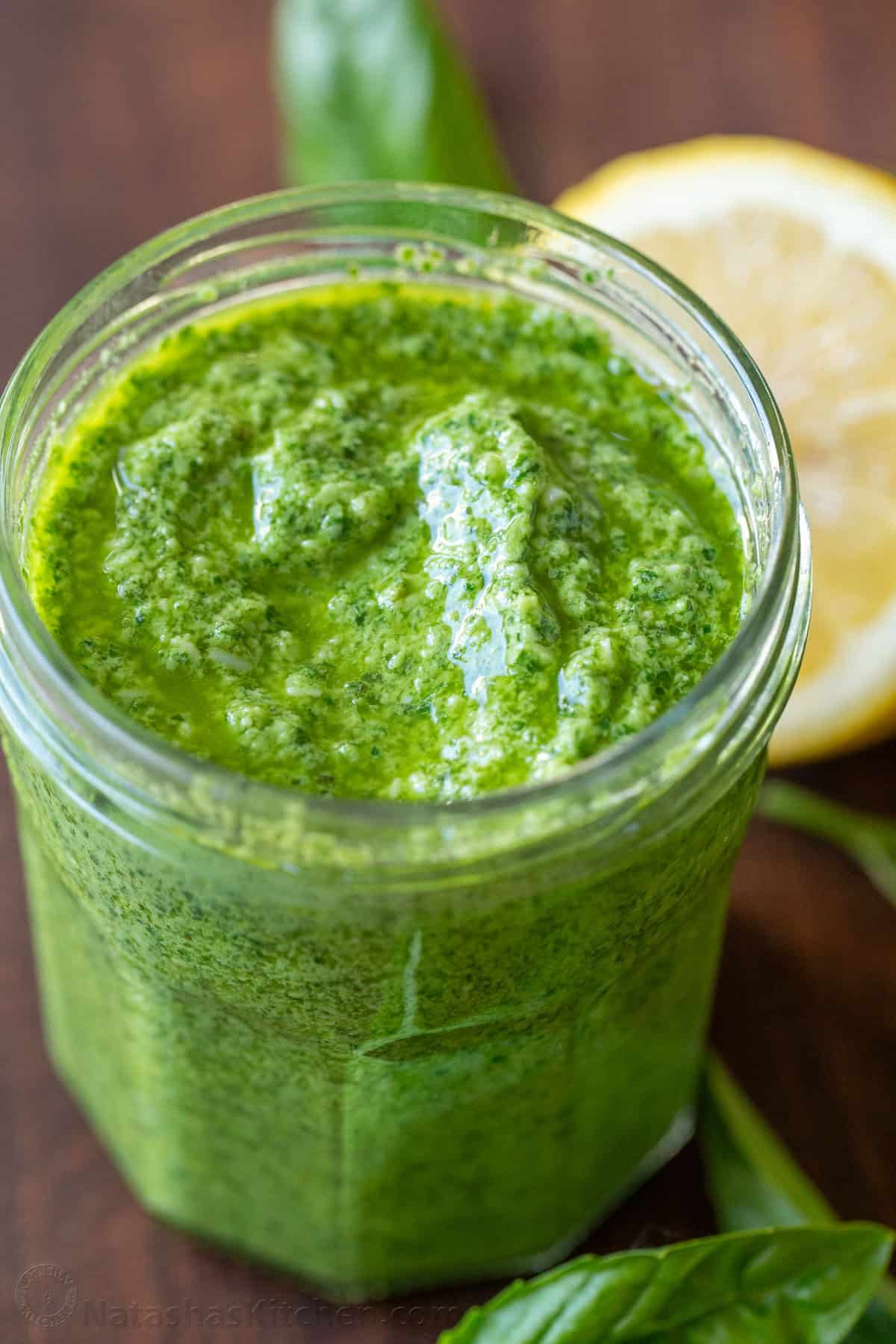 This homemade pesto tastes way better than storebought. Basil pesto is easy to make and so versatile as a sauce, dip, spread, and topping. Basil pesto in a mason jar with basil and lemon in background
