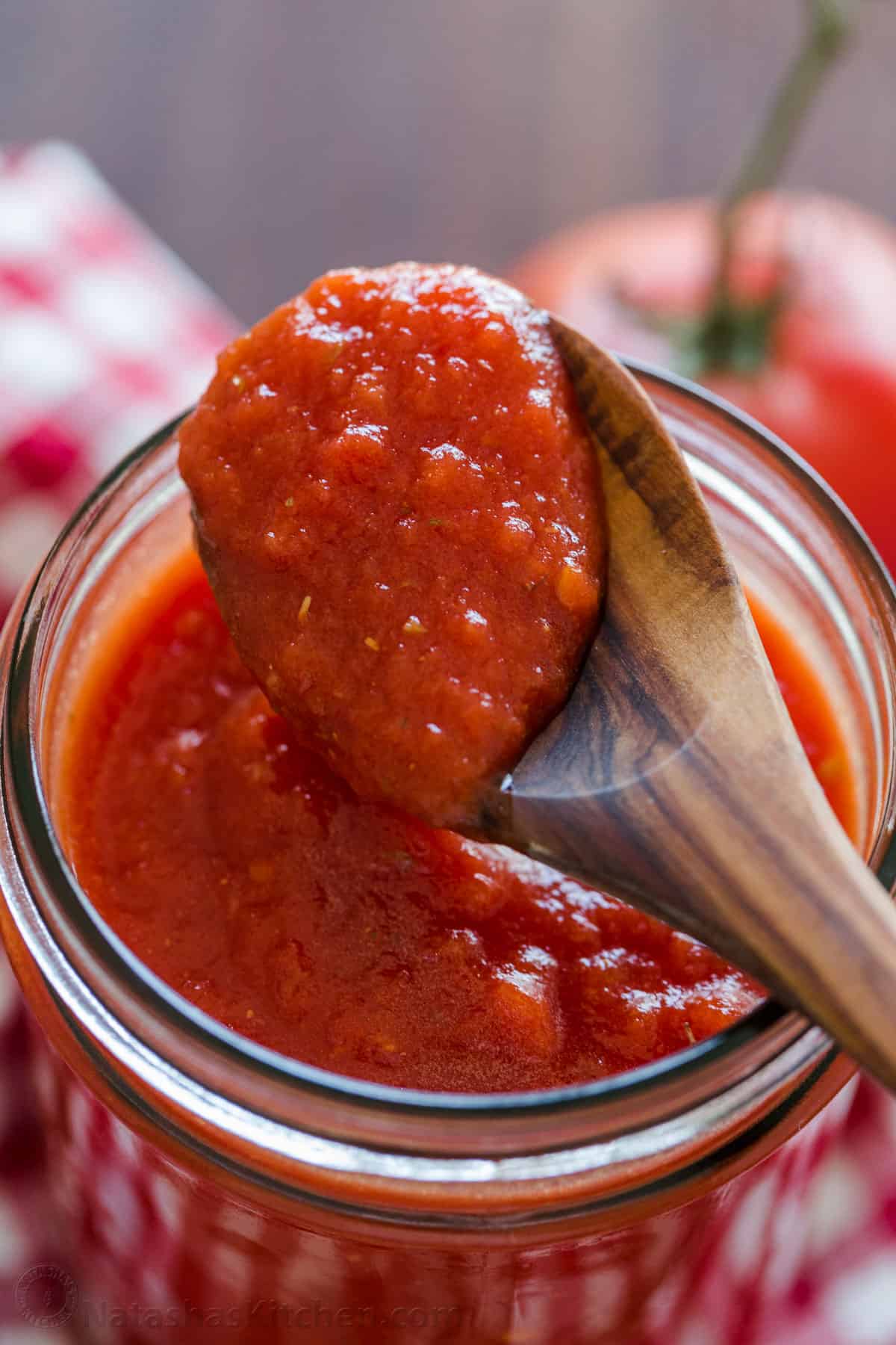 This easy pizza sauce makes for the most authentic homemade pizza. Red sauce for pizza takes just 5 minutes and 5 ingredients. No cooking! spoon scooping tomato sauce over a mason jar