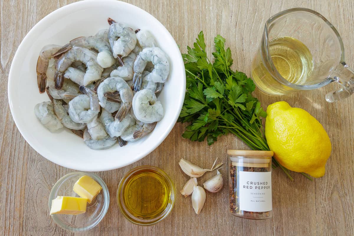 Shrimp Scampi Recipe with garlic, butter, and wine sauce drizzled with fresh lemon juice. This easy shrimp scampi takes just 10 minutes! Ingredients for seafood appetizer including raw seafood, butter, oil, garlic, parsley, white wine, red pepper flakes and lemon