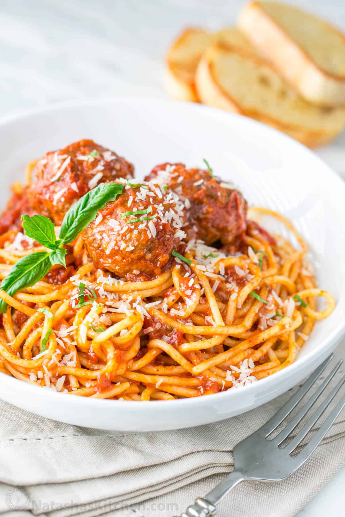 The best Spaghetti and Meatballs recipe, with big juicy meatballs and spaghetti in a homemade marinara sauce for an easy weeknight dinner. Spaghetti and meatballs served on a white plate garnished with parmesan cheese and served with a fork
