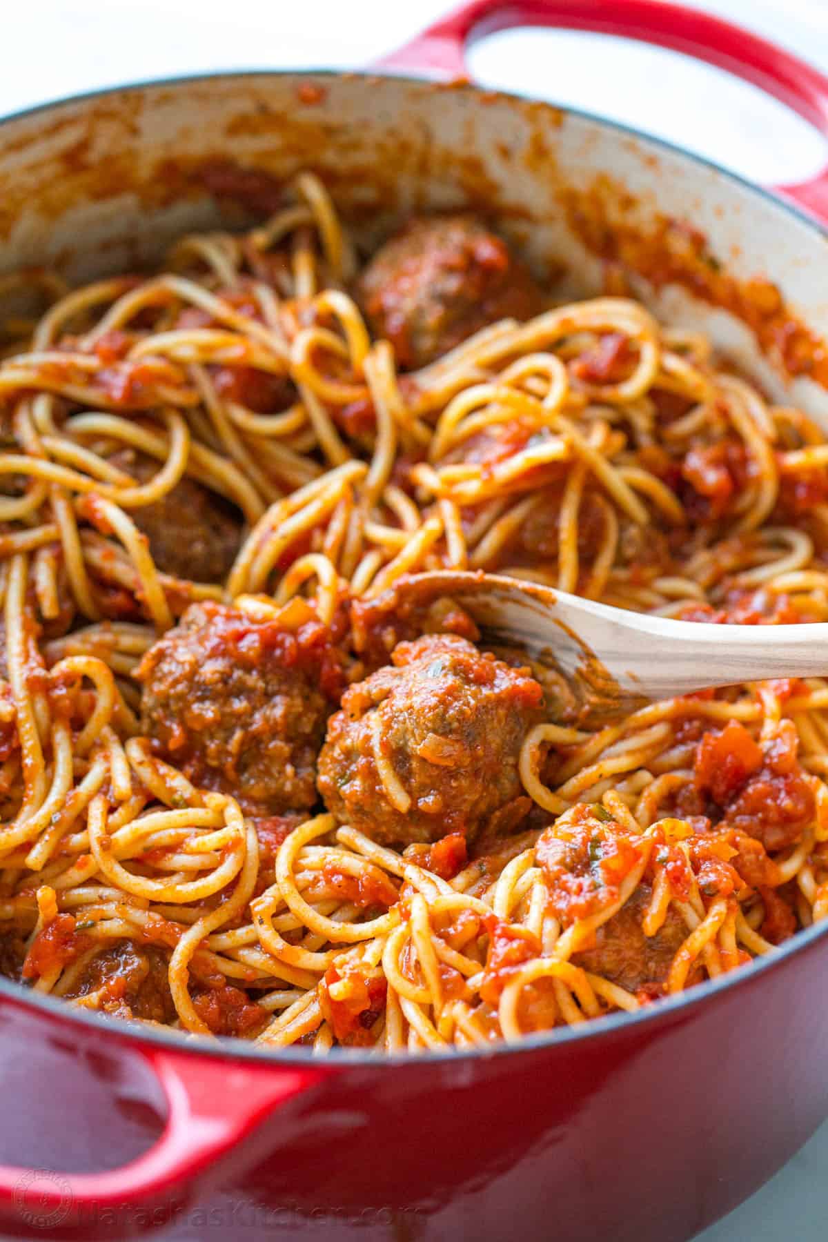 The best Spaghetti and Meatballs recipe, with big juicy meatballs and spaghetti in a homemade marinara sauce for an easy weeknight dinner. Spaghetti and Meatballs in red pot with serving spoon